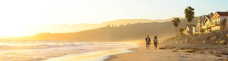 Couple walking on the beach in California near million-dollar homes