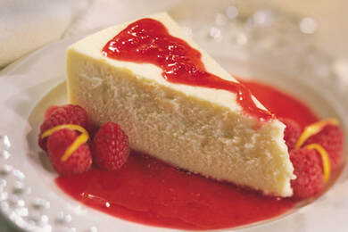 Picture of New York Style Cheesecake drizzled with raspberry sauce