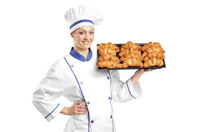 Picture of female baker in chef's hat holding tray of croissants